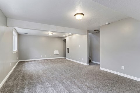 A spacious room with grey carpeting and white walls.