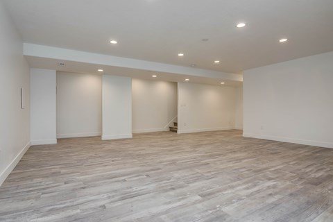 A spacious room with wooden flooring and white walls.
