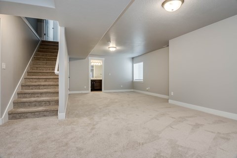 A spacious empty room with a staircase on the left side.