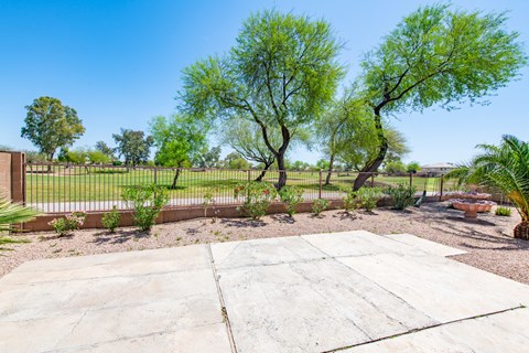 A concrete patio surrounded by a fence and trees.
