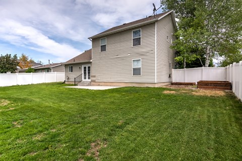 the back of a house with a yard and a white fence