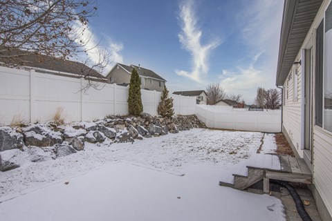 a backyard covered in snow with a fence and a house