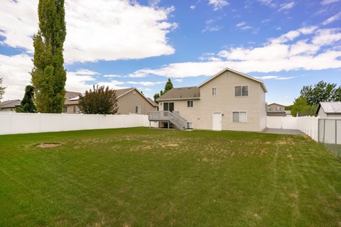 A large house with a white fence and a green lawn.