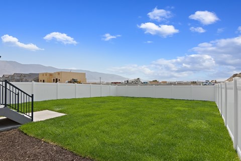 A white fence surrounds a green lawn with a building in the background.