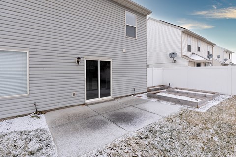 A house with a grey siding and a black door is shown.