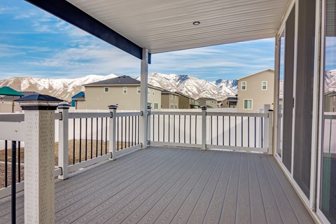 A deck with a railing and a view of houses and mountains in the background.