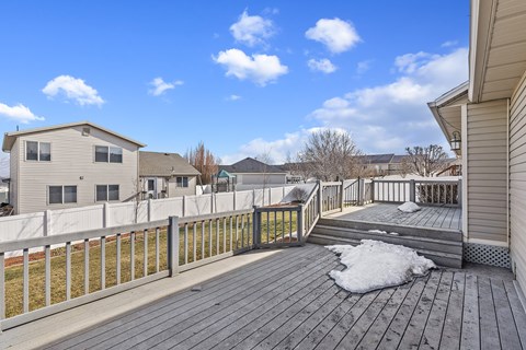 A wooden deck with a white fence and a snow patch in the middle.