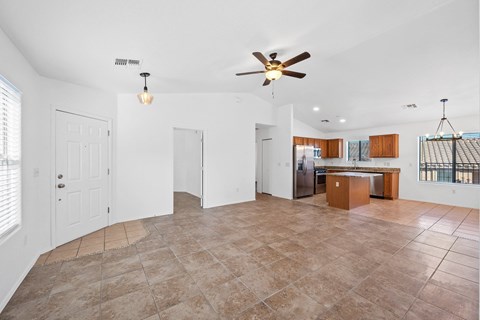 A spacious living room with a ceiling fan and tiled flooring.