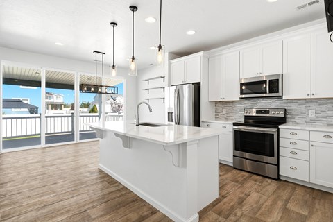 A modern kitchen with white cabinets and a wooden floor.