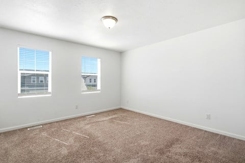 A room with carpeted floor and two windows.