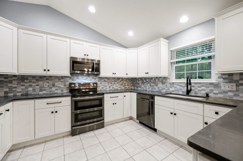 A kitchen with white cabinets and a black countertop.
