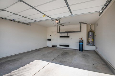 A spacious garage with a white floor and a white ceiling with a light fixture.