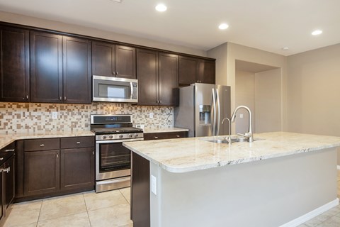 A kitchen with a white counter top and dark brown cabinets.