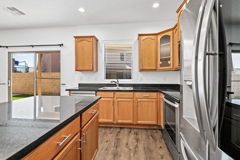 A modern kitchen with wooden cabinets and a black countertop.