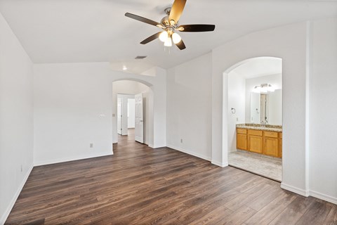 A spacious room with a ceiling fan and wooden flooring.