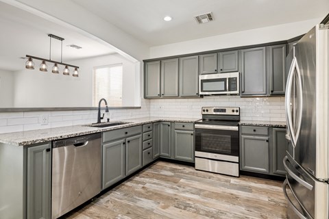 A kitchen with stainless steel appliances and grey cabinets.