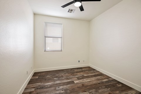 A room with a ceiling fan and a window with blinds.