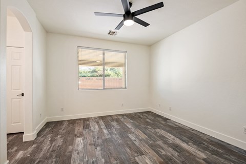 A room with a ceiling fan and wooden flooring.