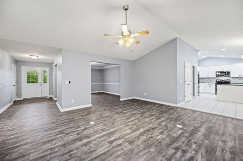A spacious room with a ceiling fan and lighting fixture.
