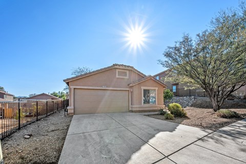 A house with a driveway and a tree in front of it.