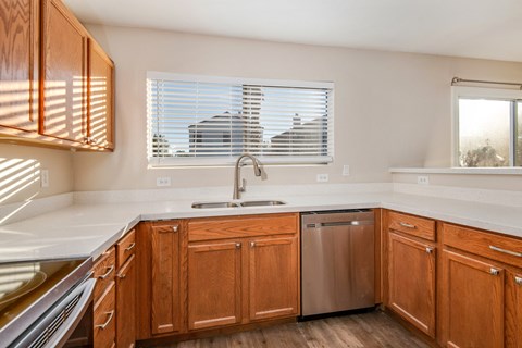 A kitchen with wooden cabinets and a stainless steel dishwasher.