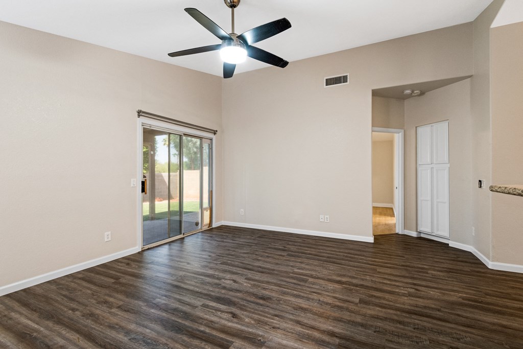 an empty living room with a ceiling fan and a sliding glass door