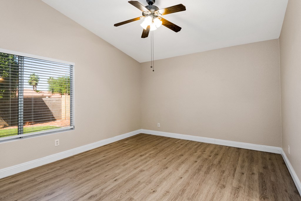 an empty bedroom with a large window and a ceiling fan