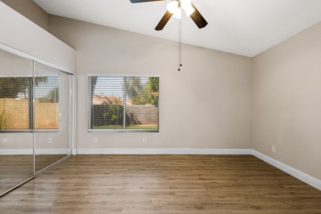 an empty living room with a window and a ceiling fan