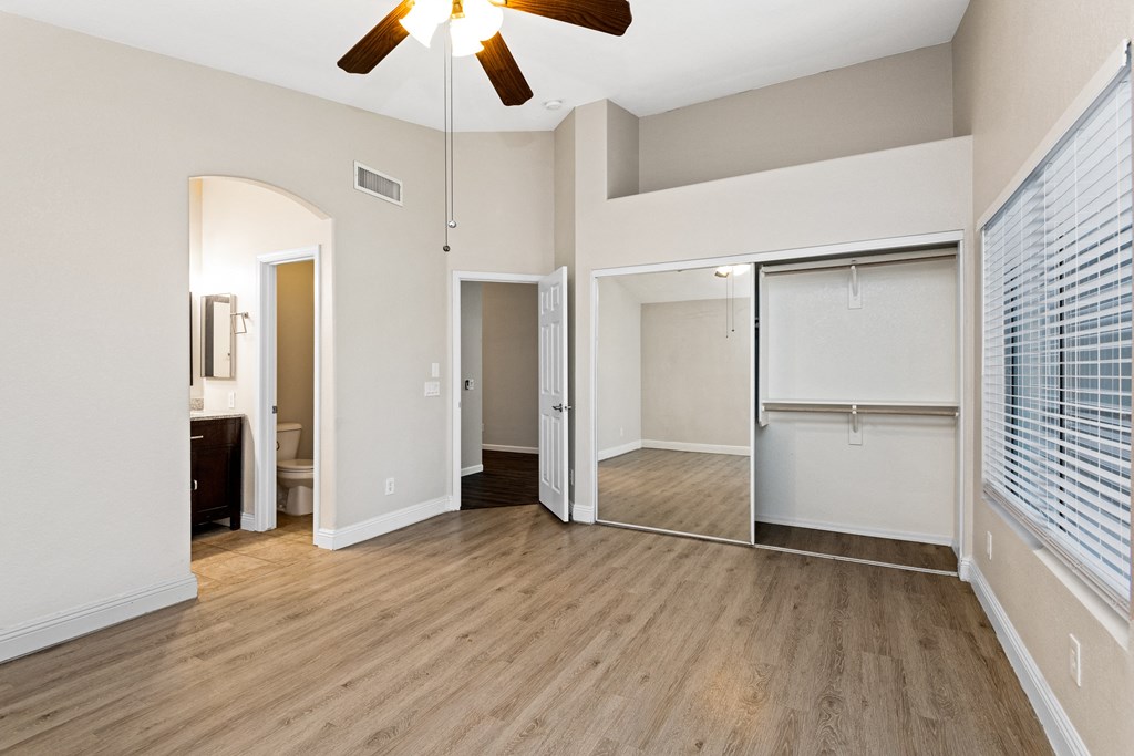 an empty living room with a ceiling fan and a closet