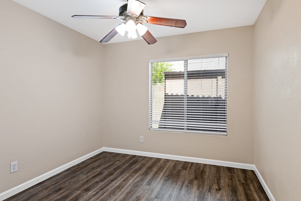 an empty bedroom with a window and a ceiling fan