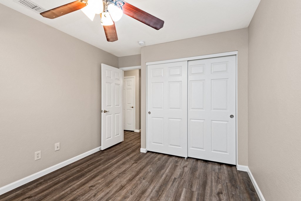 an empty bedroom with two closets and a ceiling fan