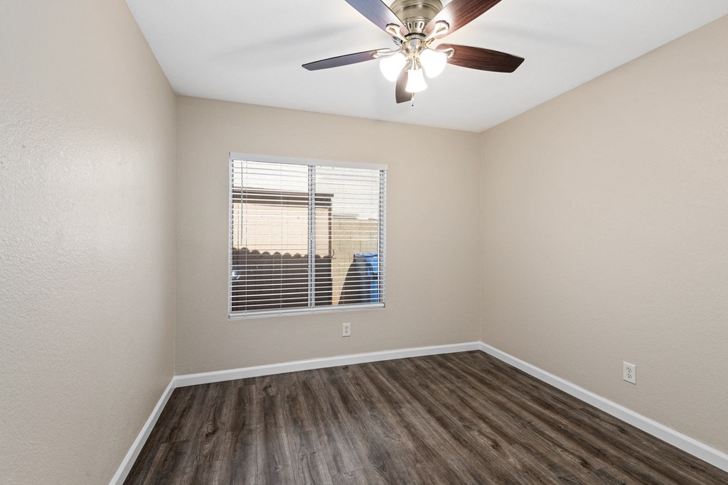 an empty bedroom with a window and a ceiling fan