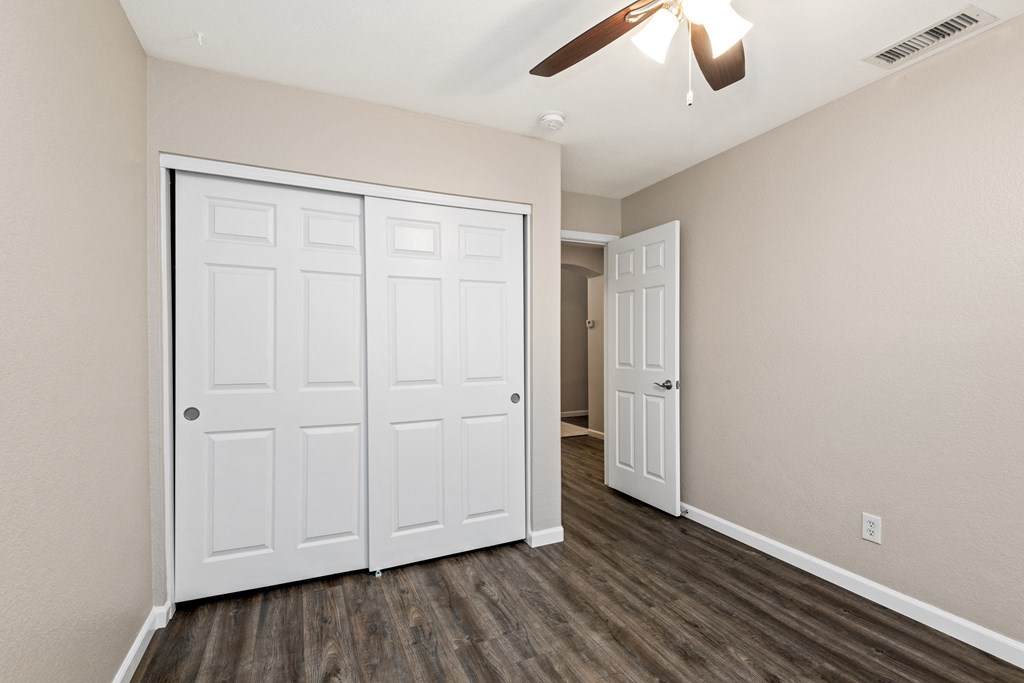 an empty bedroom with two closets and a ceiling fan