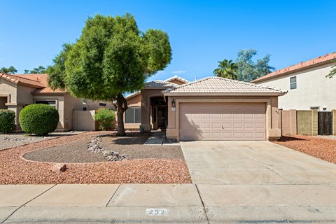 A house with a driveway and a tree in front.