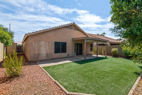 A house with a brown exterior and a green lawn in front.