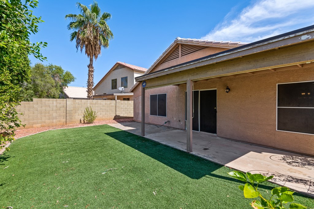 a backyard with a patio and a house with a palm tree