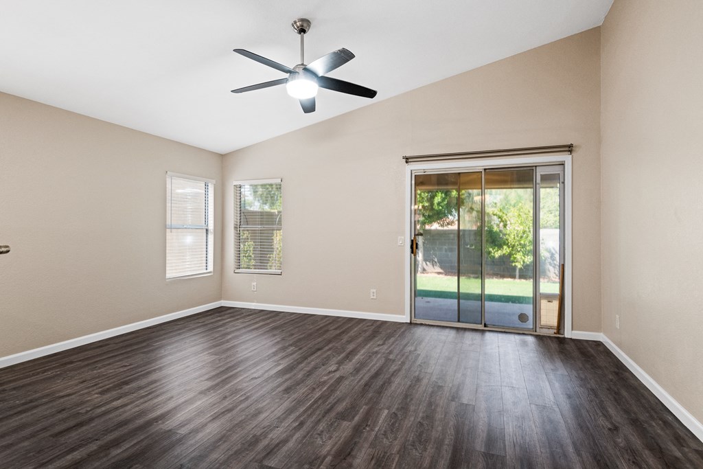 an empty living room with a ceiling fan and a glass door to a patio