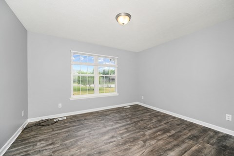 an empty living room with wood floors and a window