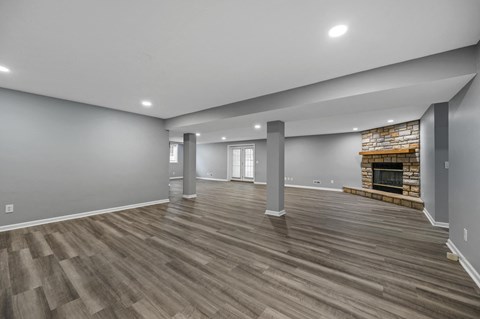 A spacious living room with wood flooring and a fireplace.