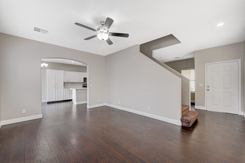 A spacious room with a ceiling fan and hardwood floors.