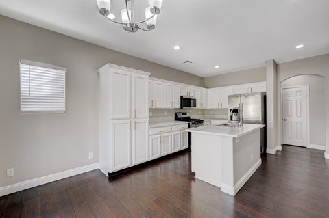 A kitchen with white cabinets and a wooden floor.