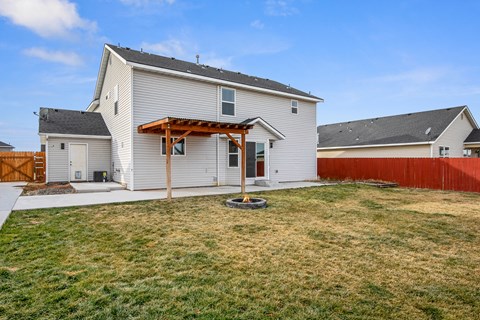 a backyard with a white house and a yard with a wooden fence