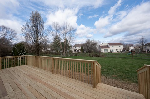 A wooden deck overlooks a grassy area with houses in the distance.