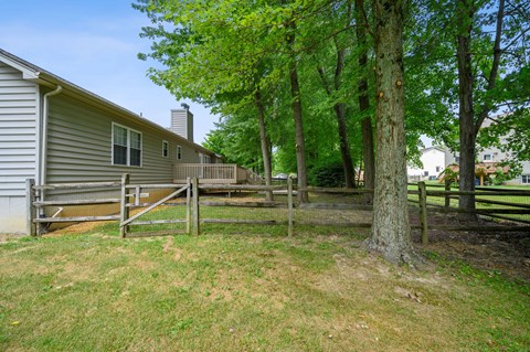 a view of the back of a house with a fence and trees