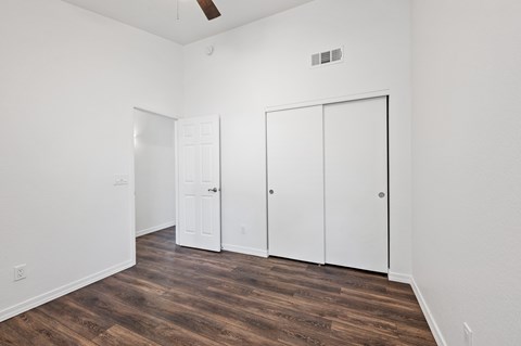 A room with a white door, a white closet, and a white ceiling fan.