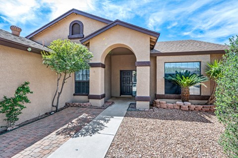 A house with a brown roof and a gravel driveway.