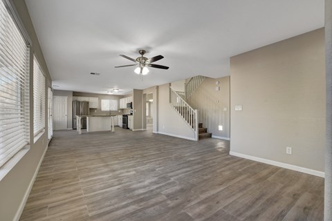 A spacious living room with a staircase and a ceiling fan.