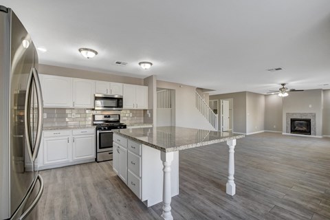 A modern kitchen with a stainless steel refrigerator and a marble island.
