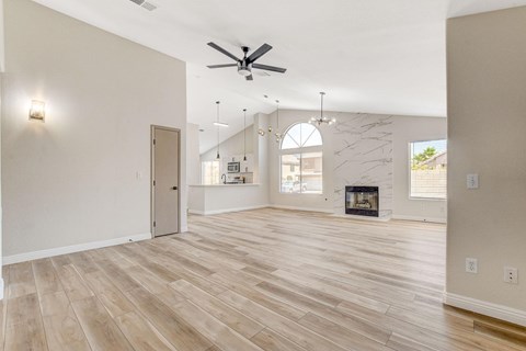 A spacious living room with a fireplace and a ceiling fan.