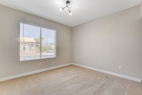 A room with a window and a carpeted floor.